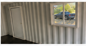 Finished interior of an Iron Box shipping container conversion, showing insulated walls, a window, and an interior door
